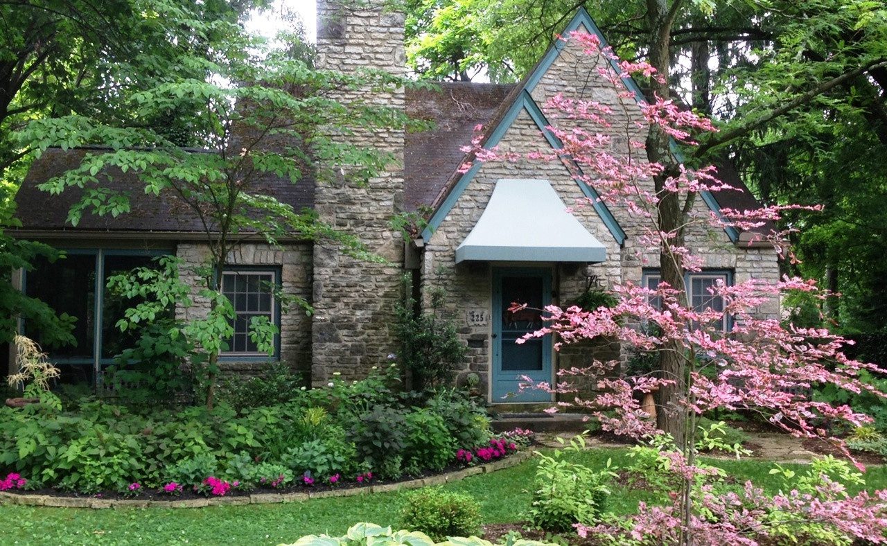 A house with pink flowers and green grass.