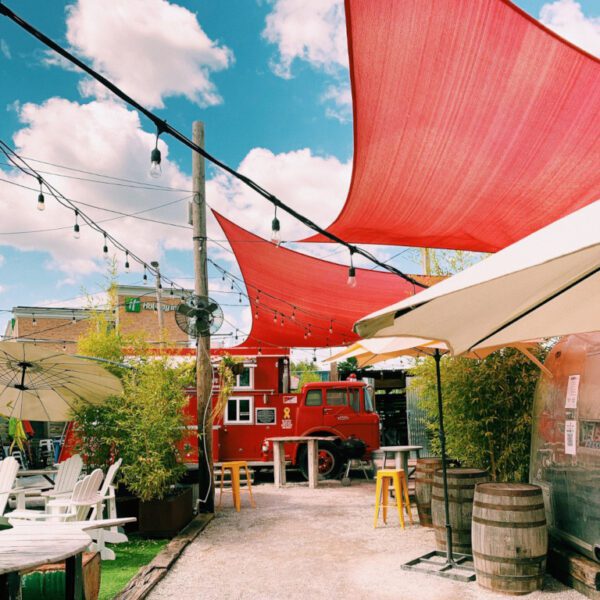 A patio with red sails and chairs on the side.